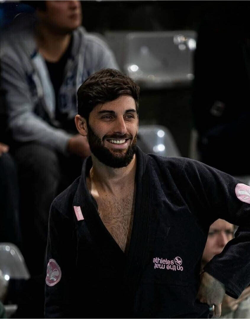 Thomas, BJJ-Athlet, während eines Jiu-Jitsu-Wettkampfs: Griffkontrolle am Boden, concentration et fair play. Foto für M.A.T – Martial Arts & Travel.